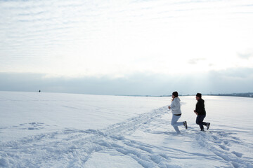 Fototapeta na wymiar Couple is jogging in the snowy field during a cold winter afternoon as part of the daily routine