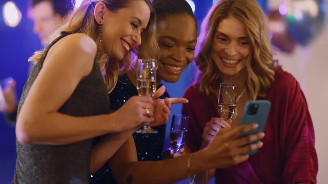 Multi-cultural friendly young three women chatting having fun on party taking photo selfie picture on smartphone. Friendship. Corporate holiday.