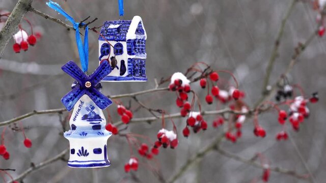 Blue ceramic Christmas toy bought in Amsterdam hangs on a branch