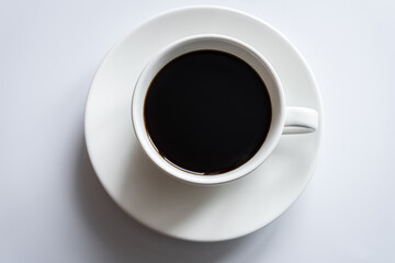 White cup of coffee stands on a saucer on a white background