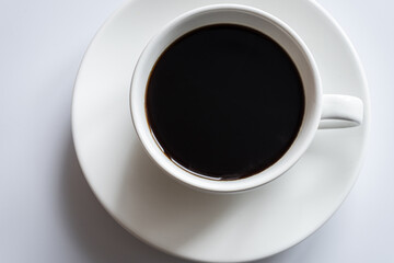White cup of coffee stands on a saucer on a white background