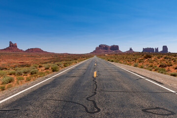 Fototapeta na wymiar Scenic view of ta road leading to the Monument Valley with sandstone buttes on the background; Concept for travel in the USA and road trip.