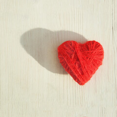 Fototapeta na wymiar Red heart made of wool threads on a light wooden background. High quality photo