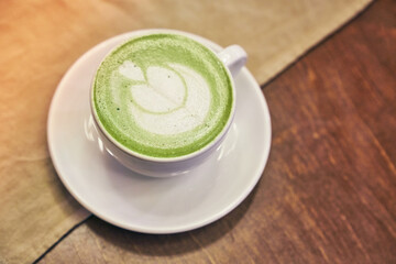 Cup of matcha latte on wooden background and a beige napkin in a cafe with copy space. High quality photo