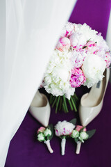 Pair of elegant and stylish bridal shoes with a bouquet with roses and other flowers