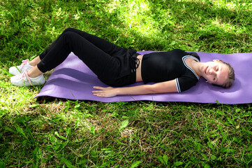 Fototapeta premium Teenager girl doing yoga in the park. Teenager resting after sports activities