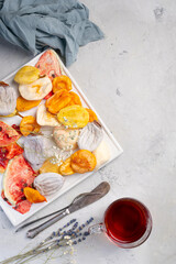 fruit chips. Dried fruits on a white plate and a light concrete background. Concept photo on a light background