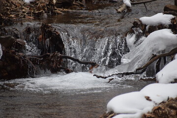 Refreshing brisk waterfall cascading over rocks and trees in the winter.
