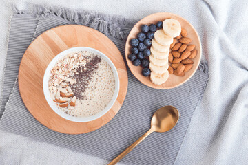 Healthy breakfast fruit smoothie bowl topped with almond, granola and chia seeds, snack banana and blueberry, flat lay