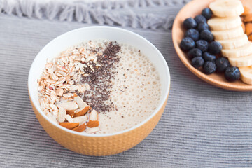 Healthy breakfast fruit smoothie bowl topped with almond, granola and chia seeds, snack banana and blueberry