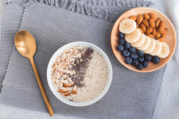 Healthy breakfast fruit smoothie bowl topped with almond, granola and chia seeds, snack banana and blueberry, flat lay