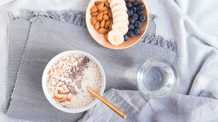 Healthy breakfast fruit smoothie bowl topped with almond, granola and chia seeds, snack banana and blueberry, flat lay