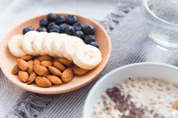 Healthy snack - almond, bblueberries, banana on wooden dish