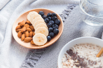 Healthy snack - almond, bblueberries, banana on wooden dish