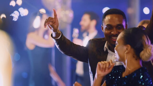 Cheerful group of multi-ethnic corporate employees in formal wear dancing together inside festive hall. Corporate party. Business people. Friendship.