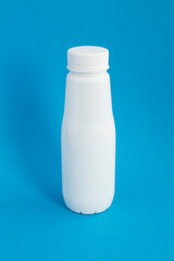 Closeup on white plastic bottle on the blue  background. Location vertical.