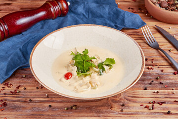 Squid in creamy cream sauce, wooden background © echo617