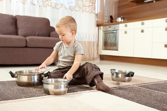 Little boy playing cooking at home in living room with kitchen.