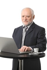 Portrait of senior businessman using laptop on coffee table, eye contact, white background.
