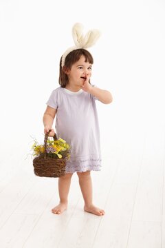 Little two years old girl wearing Easter bunny ears, isolated on white background.