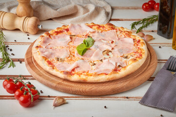 Pizza with slices, sauce and herbs, wooden white background