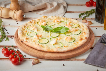 Pizza with slices, sauce and herbs, wooden white background