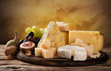 Set of different types of cheese on old wooden background, close up.