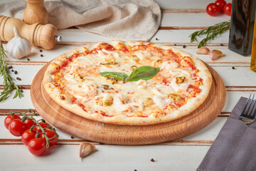 Pizza with slices, sauce and herbs, wooden white background