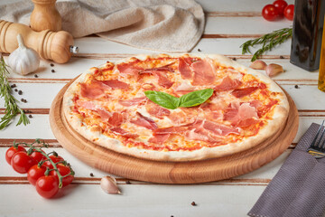 Pizza with slices, sauce and herbs, wooden white background