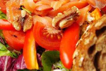 Fresh salad with smoked salmon pieces, lettuce, tomato, salad pepper and olive oil, Close up, selective focus