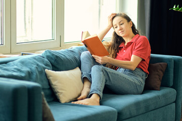 middle aged woman writing in notebook on sofa at home. beautiful woman at home writing and working with diary. Girl at home.