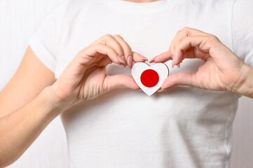 Love Japan. The girl holds a heart in the form of the flag of Japan on her chest. Japanese patriotism concept