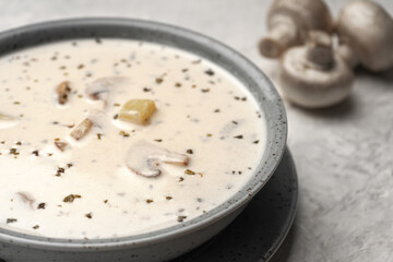 Soup with mushrooms and coconut cream in a gray plate next to raw mushrooms