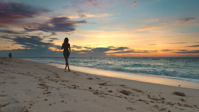 Asia sunset silhouette woman: beach sport, girl run at ocean dark coastline on sand shore of Boracay Island, Philippines. Picturesque sun set recreation on tropic resort in golden tones. Shot 4K, UHD