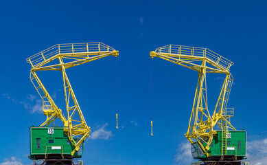 two colorful industrial cranes on a blue sky background