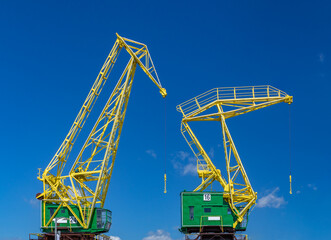 two colorful industrial cranes on a blue sky background