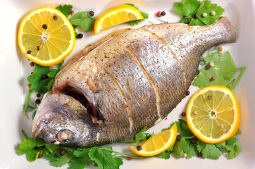 Dorado fish baked with lemon and parsley lies on a platter.