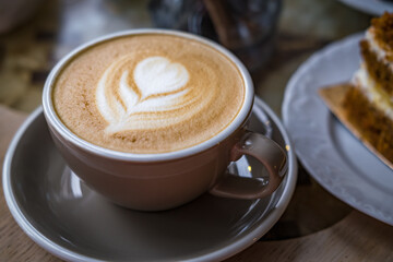 cappuccino and a slice of cake on a plate in a cafe