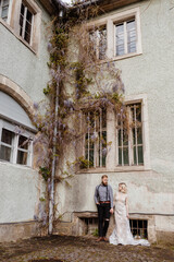 Gorgeous wedding couple hugging and walking near old castle in sunny beautiful park. Stylish beautiful bride and groom posing on background of ancient columns and nature