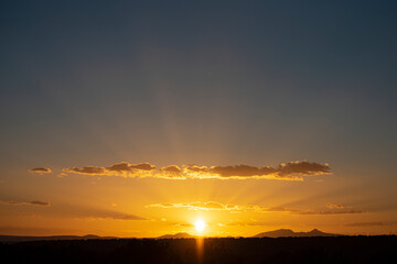 Natural sunset sunrise. Bright dramatic sky and dark ground. Countryside landscape under scenic colorful dawn. Sun over Skyline, Horizon. Warm heaven.