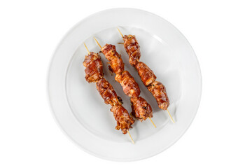 Grilled bacon-wrapped chicken tenders are laid out on a white plate. Strung on wooden skewers.