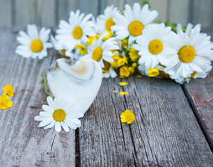 Obraz premium Marble heart and daisy flowers on an old wooden table. Vintage Valentine background. 