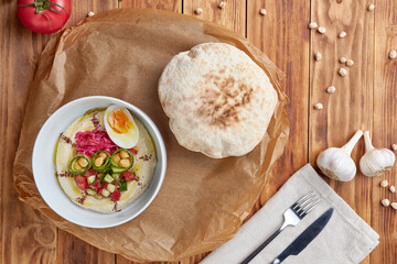 Hummus bowl with pita, pita, wood background