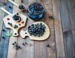 Black currant jam with black currants fresh berries on a wooden background
