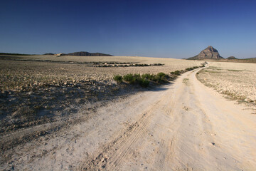 Camino hacia la montaña. Camino agrícola entre campos de secano con pico de El Almorchón al fondo. Llanos de Cagitán, en el interior de Murcia.