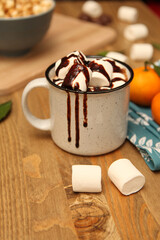 a cup of hot chocolate with marshmallows on a wooden background