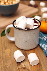 a cup of hot chocolate with marshmallows on a wooden background