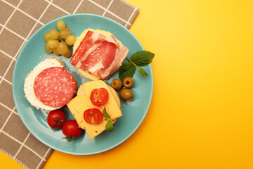 Three open sandwiches with soft cheese, tomatoes, meat and bacon on a plate. Image of the top view.