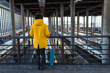 Woman in yellow coat prepares to skate with her skateboard.