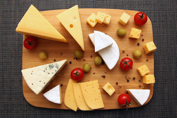 Mix the cheese on a wooden board with the grapes and cherry tomatoes. The view from the top.